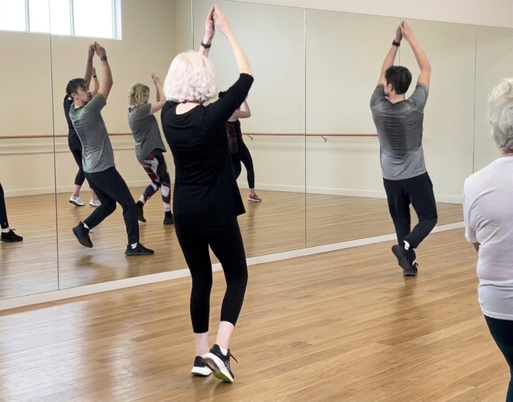 A Kinetics 360 class moving together, arms raised toward the studio mirror